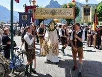 Fronleichnamsseeprozession in Traunkirchen 2017. Dieses Bild zeigt einen Piester unter einem getragenen Himmel mit der Monstranz mit dem Leib Christi : Fronleichnamsprozession, Fronleichnamsseeprozession, Seeprozession, Traunkirchen, Traunsee, Ortsplatz, Priester, Monstranz, Leib Christi, Allerheiligstes, Fahrrad, Träger, Traeger